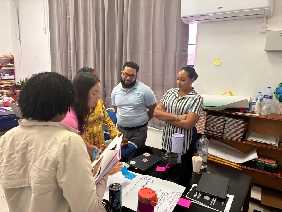 Staff gather around a table reviewing chart paper and notes in a classroom