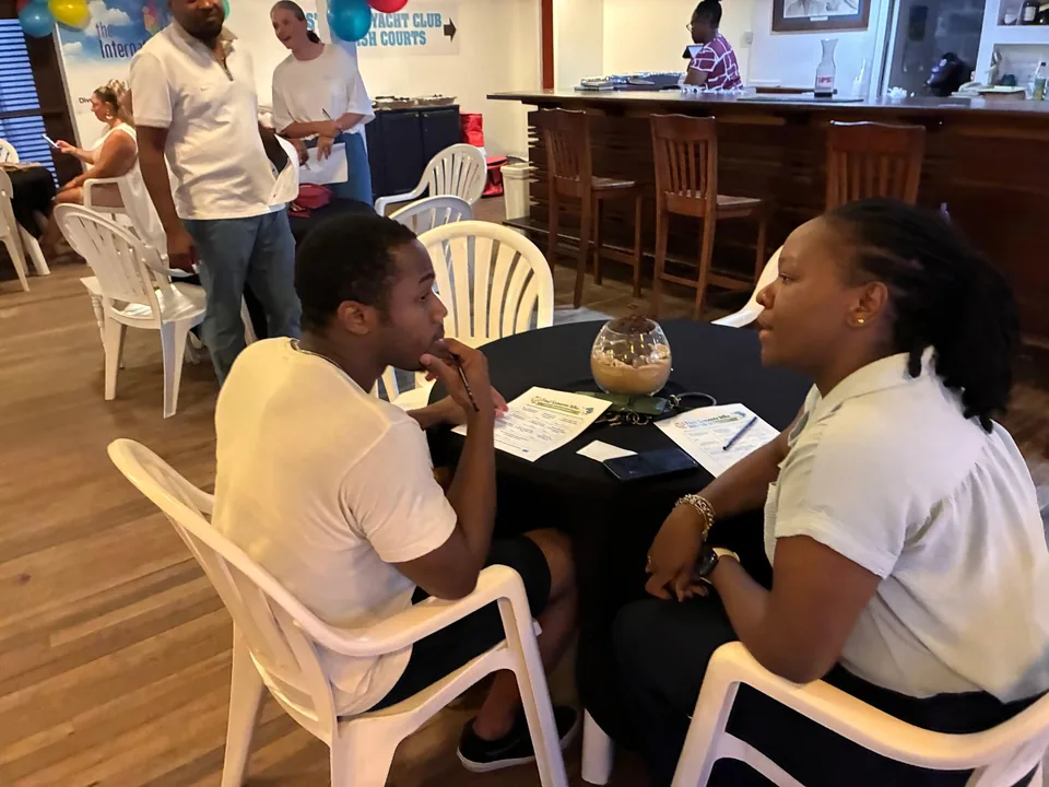 A young man and a staff member talk across a round table covered in handouts