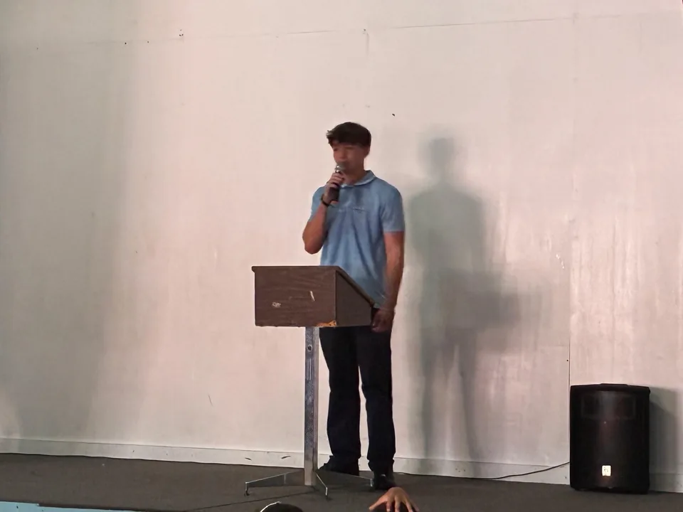 A student in uniform gives a campaign speech into a microphone at the lectern