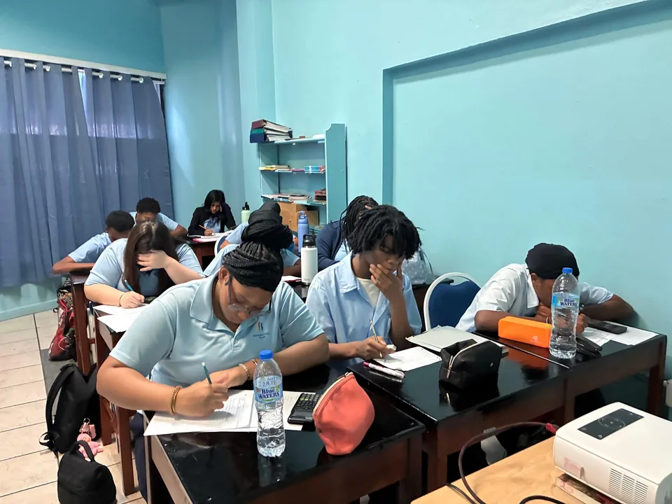 Secondary students work on papers with calculators at desks in a blue classroom