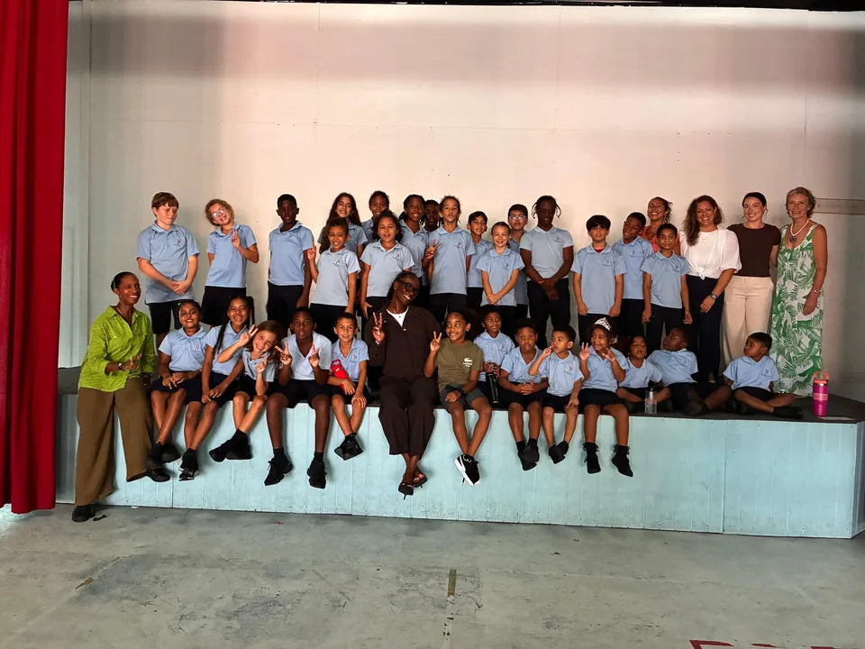 Students and staff gather on the hall stage for a group photo during Julien Alfred's visit