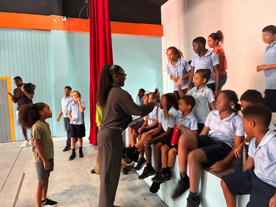 Julien Alfred talks with younger students seated on the stage steps