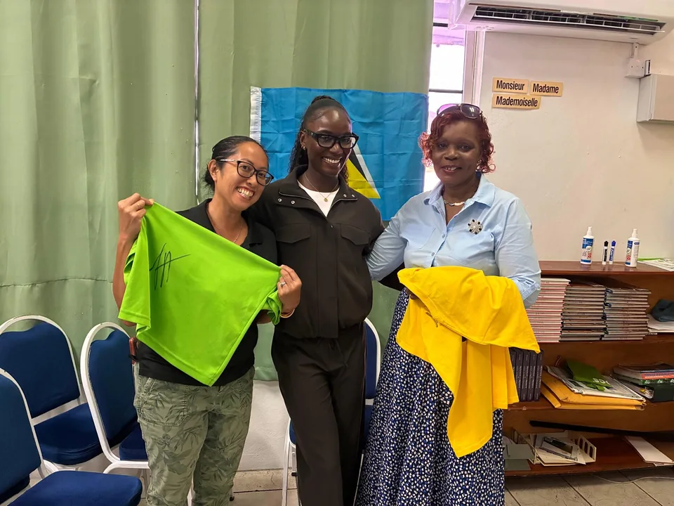 Julien Alfred with two staff members holding up green and yellow T-shirts